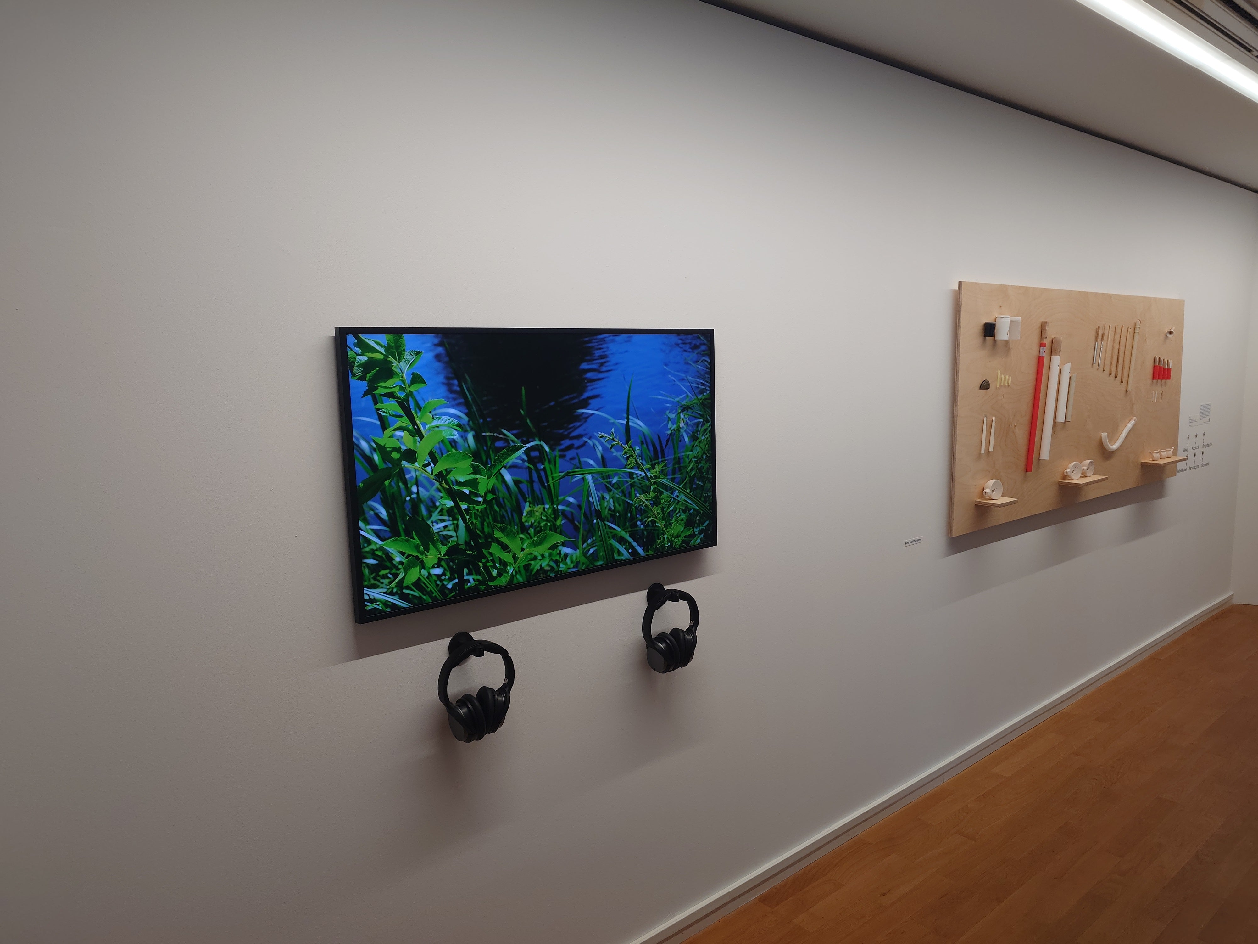 Two wall-mounted headphones beneath a museum video display